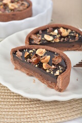 luxury home baked rocher dark rich chocolate tart in 3 layer with hazelnut mixed nuts and gold foil in white background halal dessert menu for hotel cafe