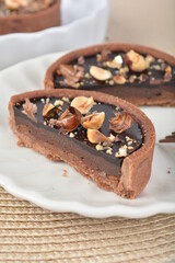 luxury home baked rocher dark rich chocolate tart in 3 layer with hazelnut mixed nuts and gold foil in white background halal dessert menu for hotel cafe