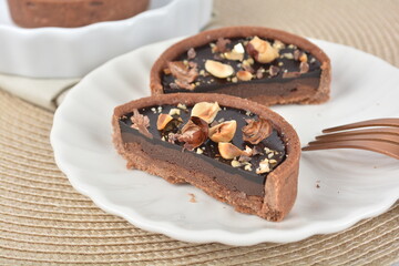 luxury home baked rocher dark rich chocolate tart in 3 layer with hazelnut mixed nuts and gold foil in white background halal dessert menu for hotel cafe