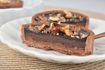 luxury home baked rocher dark rich chocolate tart in 3 layer with hazelnut mixed nuts and gold foil in white background halal dessert menu for hotel cafe