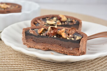 luxury home baked rocher dark rich chocolate tart in 3 layer with hazelnut mixed nuts and gold foil in white background halal dessert menu for hotel cafe