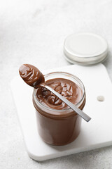 Spoon with Chocolate sauce on glass jar and white board. Liquid chocolate. Copy space