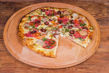 Pizza with different sausages on the round wooden pizza board