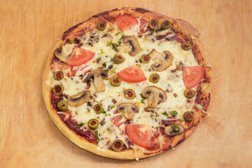 Pizza with chicken, mushrooms, tomatoes, olives on cutting board