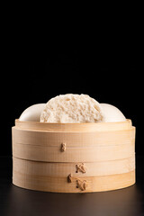 Chinese food steamed buns in bamboo on black background