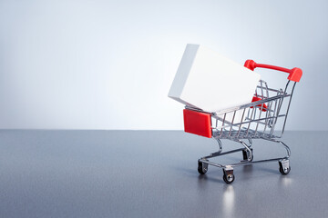  shopping cart with boxes on grey background with copy space.  Sale, discount, shopping, delivering service concept. © Sergey
