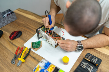 The young master electronics engineer checks, repairs and finishes the motherboard he was given to...