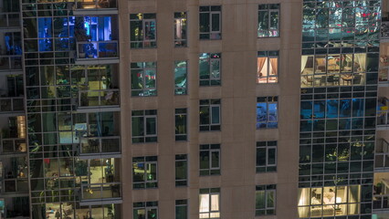 Fototapeta na wymiar Windows in high-rise building exterior in the late evening with interior lights on timelapse