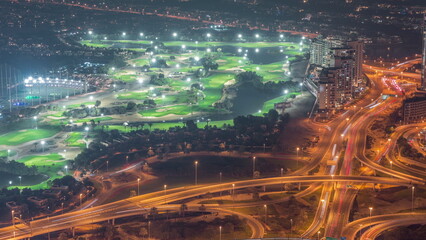 Aerial view to Golf course with green lawn and lakes, villas and houses behind it night timelapse.