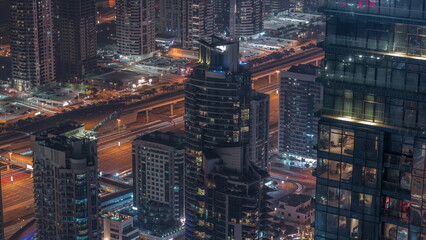 Futuristic buildings of Dubai with metro station and luxury skyscrapers behind near Dubai Marina night timelapse