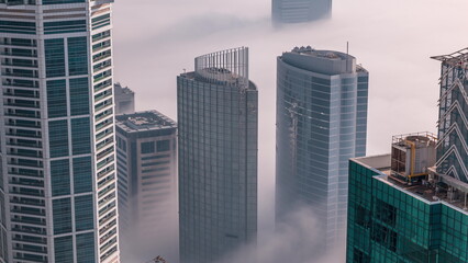 Fototapeta na wymiar Rare early morning winter fog above the Dubai Marina skyline and skyscrapers rooftops aerial timelapse.