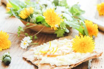 Fototapeta na wymiar Essbare Blüten Butterblumen Salat Wildkräuter Tisch Brett