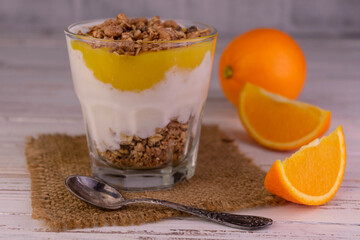 Parfait of orange yogurt and granola in a glass. Healthy low calorie dessert food