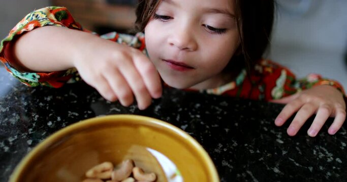 Child eating cashew nuts from bowl