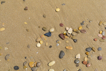 Fototapeta na wymiar Sandy sea beach with small colored stones, natural coastal background