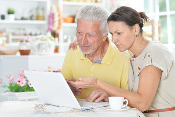 Senior man with young woman using laptop