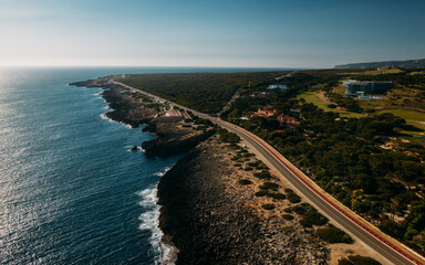 Aerial view top down view of of a straight road and rugged coastline at Guincho beach, Cascais,...