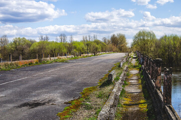 An old road bridge over a river with a broken railing