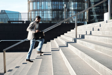 African American white collar worker running up the steps towards modern business center, blurred...