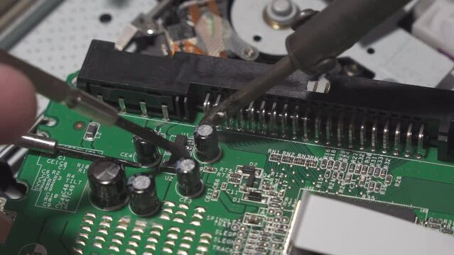 Repair of digital electronic board. The repair engineer works with a soldering iron.
