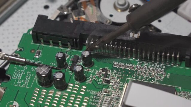 Repair of digital electronic board. The repair engineer works with a soldering iron.
