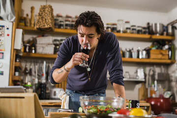 man tasting wine in kitchen