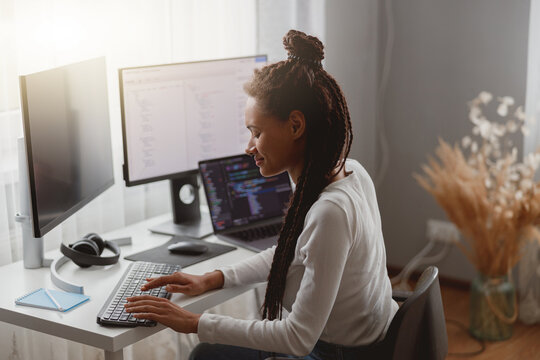 Happy mixed-race woman programmer works in room at home, distance freelance work