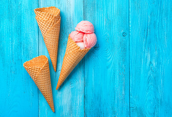 Strawberry ice cream and waffle cones on a blue background. Summer background.