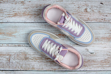 New colored sneakers with white laces on a colored wooden background, close-up. Fashion footwear. Top view, flat lay.