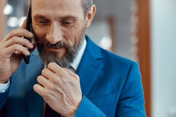 Smiling businessman holding his hand to his chin during a telephone conversation