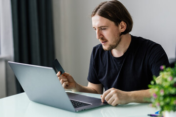 Fototapeta premium Modern technology, business, career, e-commerce and online trading concept. Businessman holding credit card in one had and keyboarding on laptop with other hand, making transaction