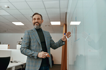 Happy mature businessman presenting important information on white board