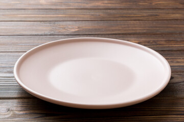 Perspective view of empty pink plate on wooden background. Empty space for your design