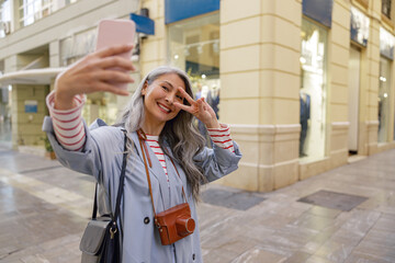 Attractive mature woman with smartphone on city street