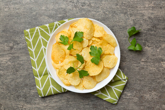 Potato chips on bowl with napkin on colored background. Delicious crispy potato chips in bowl. Space for text. Top view