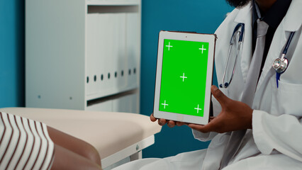 General practitioner holding digital tablet with greenscreen at consultation appointment in offce. Medic using isolated mockup background with blank copyspace and chroma key template. Close up.