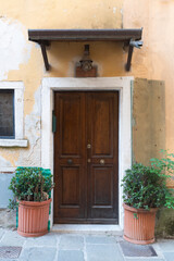 Fototapeta na wymiar Ancient door of an Italian house with marble portal and canopy