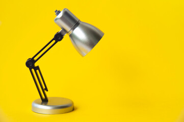 Closeup silver and black small lamp on yellow color background. Copy space concept