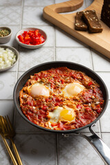 Shakshuka in a frying pan. Traditional Israeli fried eggs cooked in tomato sauce with red paprika, onion and spices. Breakfast concept