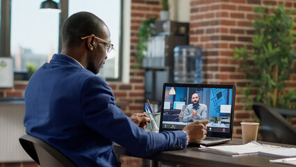 Company employee attending remote videocall meeting with man on laptop, having conversation on...