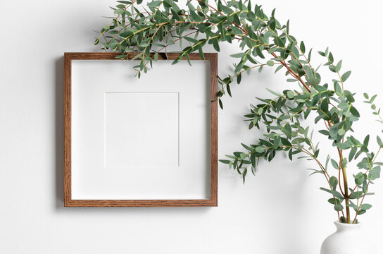 Square frame mockup in white room interior with fresh eucalyptus plant in vase