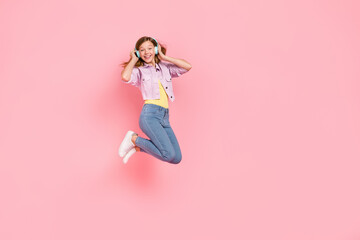 Photo of funny carefree inspired lady jump listen favorite song wear earphones jacket isolated pink color background