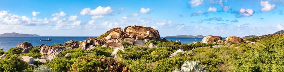 Virgin Gorda,  Felsen aus Granit an der K&uuml;ste auf der karibischen Insel und blauer Himmel mit Wolken als Panorama.