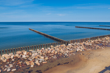 Obraz premium Breakwater wooden structures with blue sea and sky in the background. Stock photo