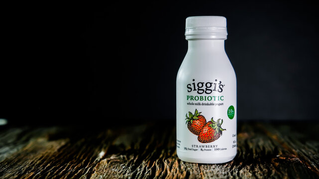 Siggis probiotic whole milk drinkable yogurt with strawberry on wooden rustic table in plastic bottle