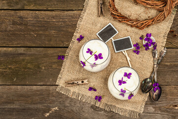 Vegan panna cotta dessert with fresh violet flower. Striped very peri color food, rustic style