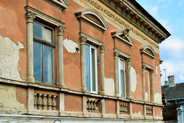 Naklejka premium fragment of a row of windows with gables and cornice on the facade of an old house in the historic city