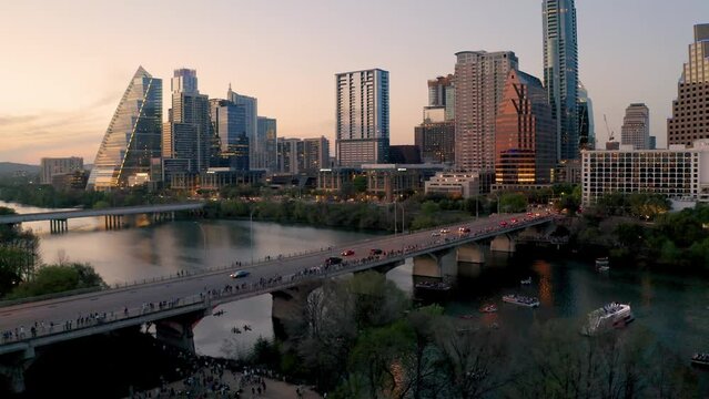 Downtown Austin Texas skyline in summer 2022, buildings reflecting sunset at golden hour aerial drone over South Congress bridge and Town Lake as tourists await bats