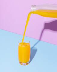 Orange juice glass on a blue table. Pouring orange juice.