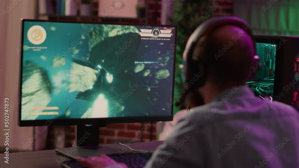 Aufkleber overs shoulder view of gamer streaming fast paced space shooter action game on gaming pc. man playin